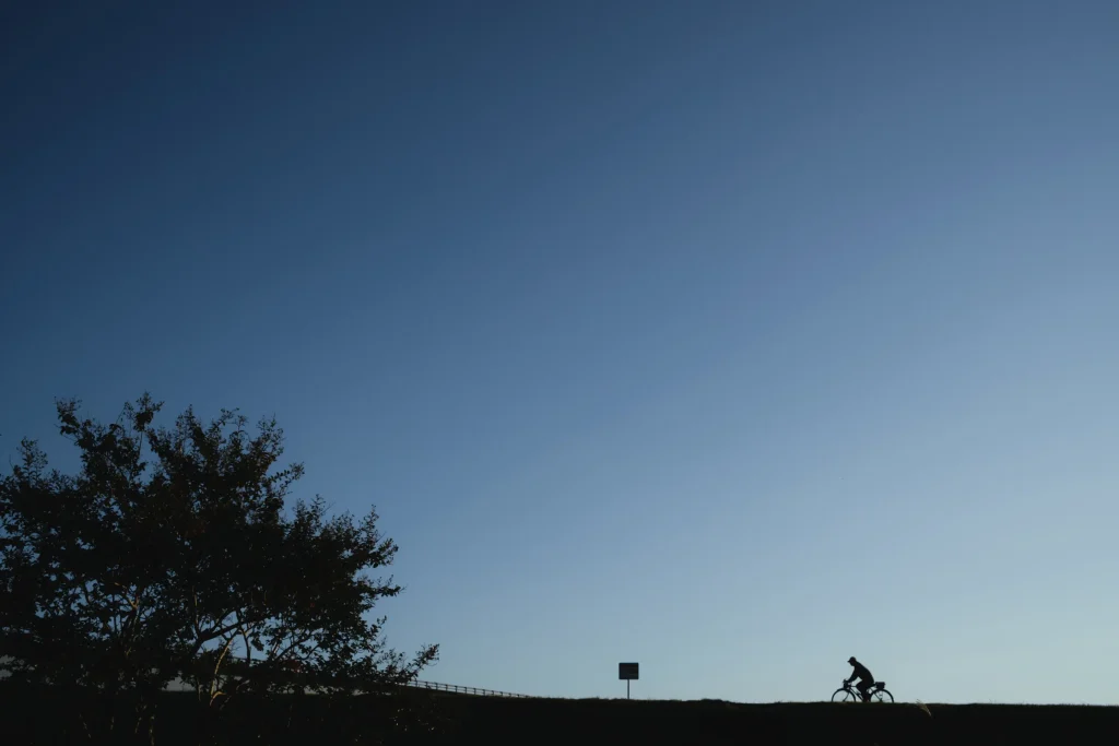 自転車で走る人のシルエットと空